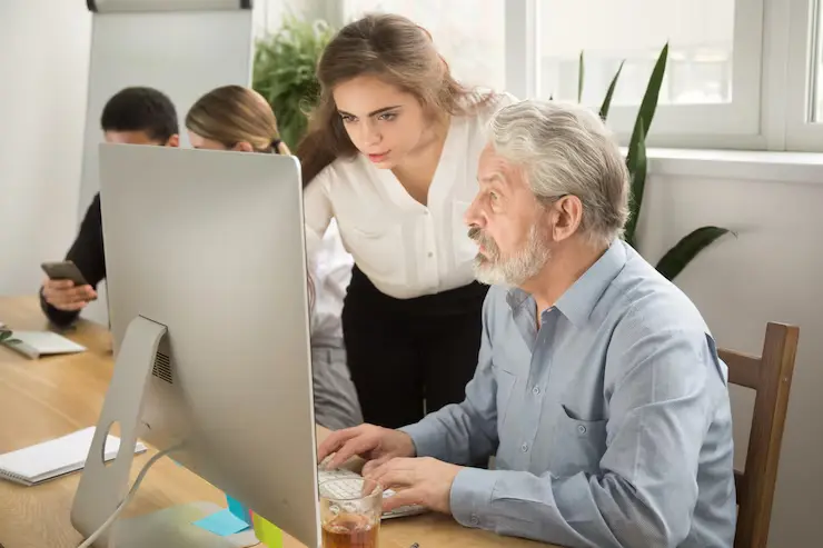 Female executive teaching senior office worker helping explaining computer work 1163 4903
