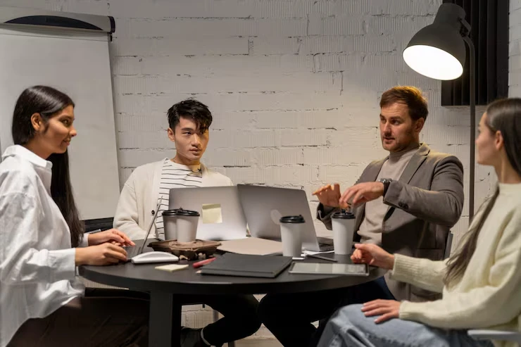Professional team discussing B2B appointment setting strategies around conference table with laptops