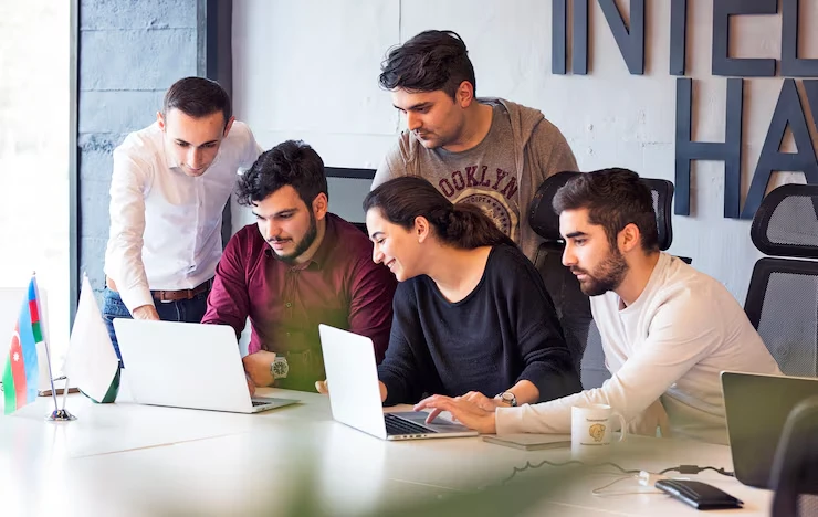 Sales team collaborating on CRM and follow-up systems with laptops in modern office workspace