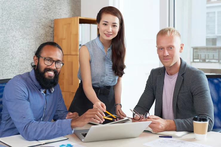 Diverse professional team planning campaigns by industry vertical with laptop and documents in office