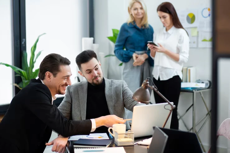 Sales team working with integrated technology systems and laptops in collaborative office setting