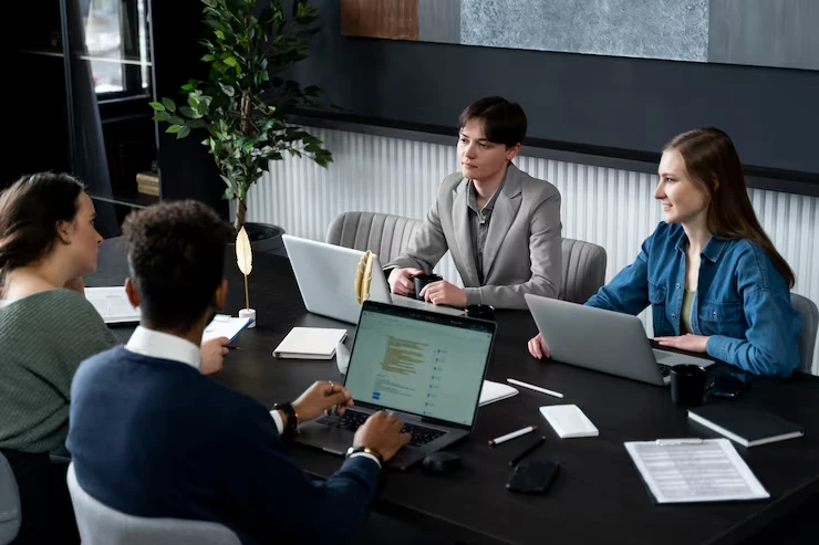 Professional team meeting discussing LinkedIn lead generation strategies for annuity advisors with laptops and data
