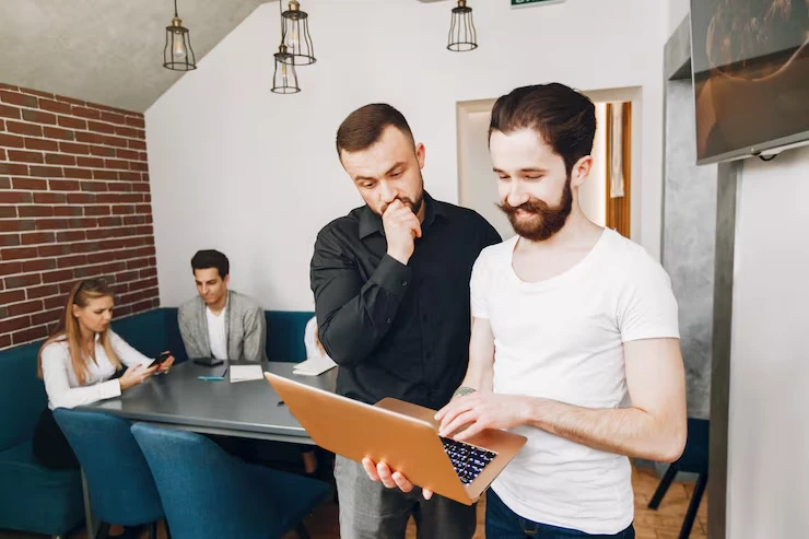 Professionals using laptop for LinkedIn outreach strategy in modern office environment