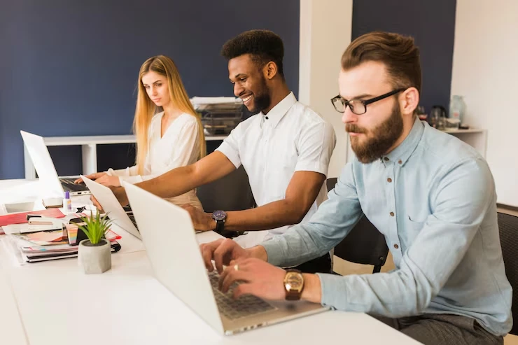 Three professionals developing personal loan campaigns on laptops in modern office workspace