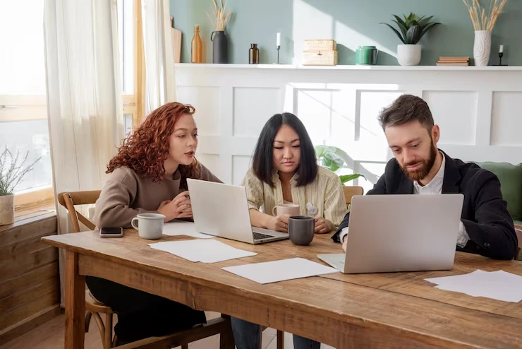 Three professionals working on laptops demonstrating real-time CRM integration workflow in bright office