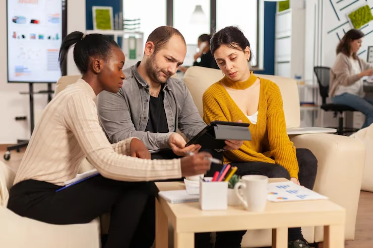 Three professionals reviewing warm transfer lead data on tablet in collaborative office environment