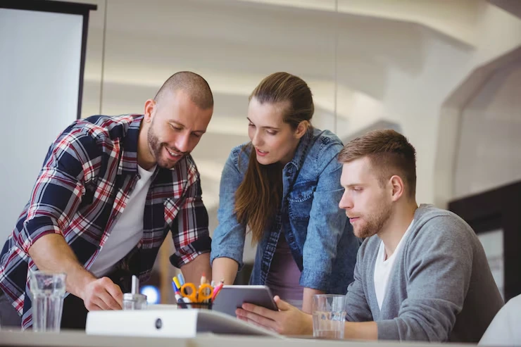 Three tech specialists configuring CRM integration on tablet in modern office workspace