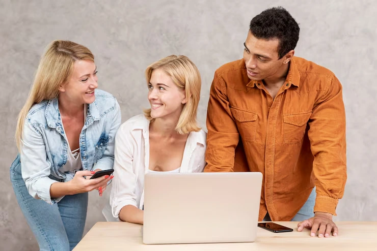 Marketing team reviewing cold email campaign results on laptop with mobile phone for multi-channel approach