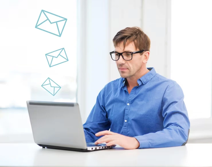 Business consultant typing on laptop with email icons floating above, creating outreach campaigns