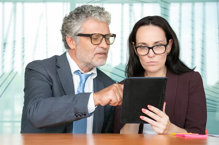 Senior consultant is explaining GDPR compliance requirements to business executive using tablet in bright office