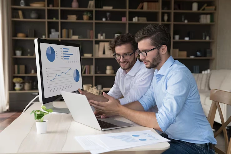 Two professionals analyzing lead conversion charts and growth metrics on computer screen and printed reports