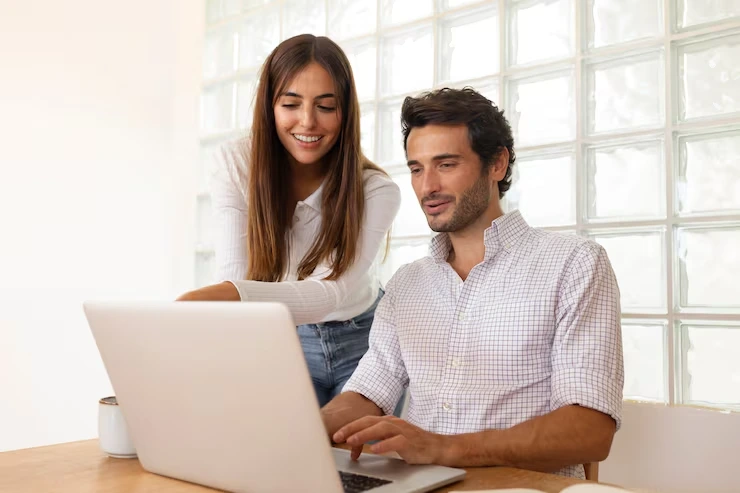 Female copywriter reviewing email draft with male client on laptop in bright office setting
