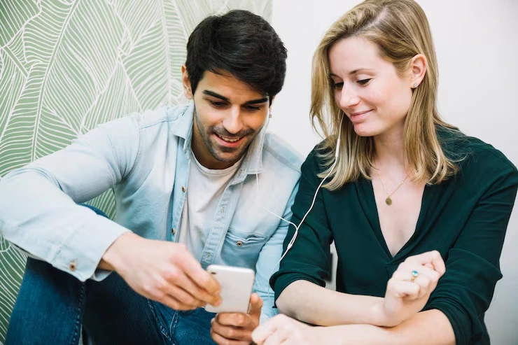 Man showing woman personalized text message on smartphone while she reviews campaign content