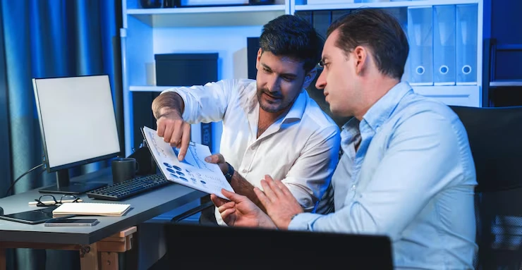 Data specialist showing prospect list results to client using printed reports in modern office