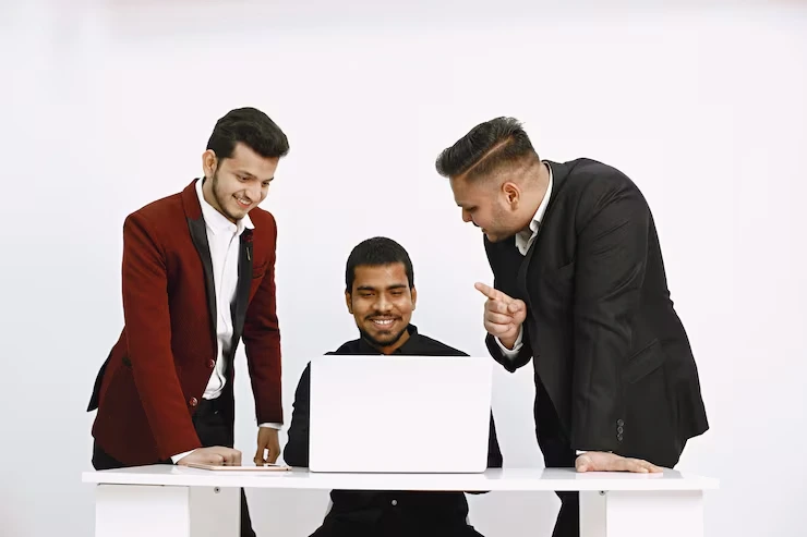Three business professionals celebrating successful lead generation campaign results while reviewing performance data on laptop
