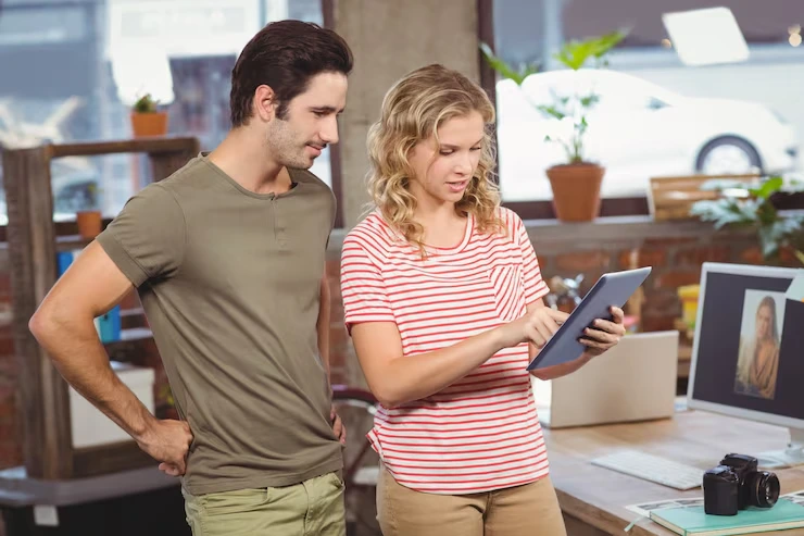 Marketing consultant reviewing retargeting campaign analytics on tablet with business owner in office