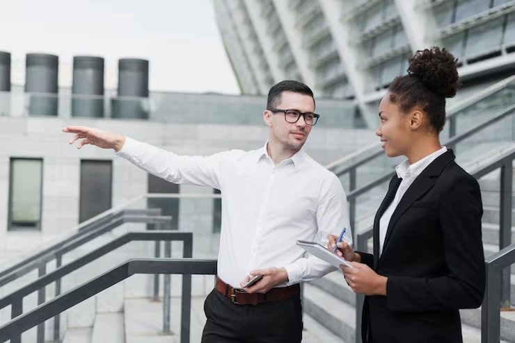 Business consultant explaining lead nurturing strategy to professional woman with tablet outside modern office