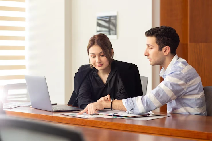 Sales professionals reviewing appointment scheduling data and prospect documents on laptop at conference table