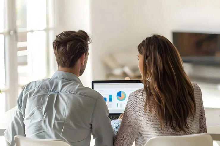 Two professionals analyzing conversion metrics and performance data on laptop screen