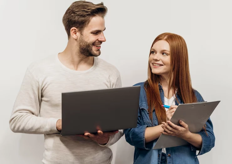 Two professionals comparing lead data on laptop and clipboard while smiling