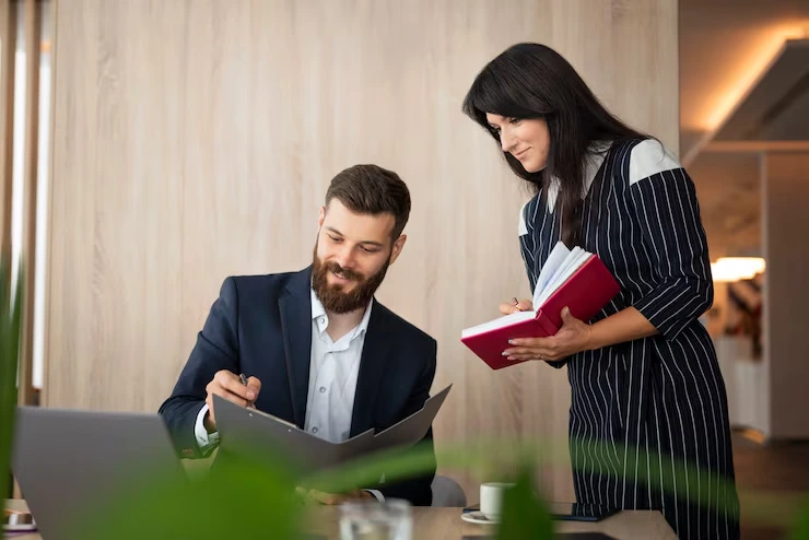 Business professional reviewing lead qualification documents while colleague references detailed criteria notebook