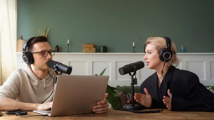 Business professional explaining pitch strategy to client during podcast recording session with laptop and microphones
