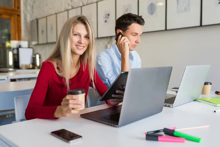 Lead generation team member working at laptop while colleague handles client call in modern office