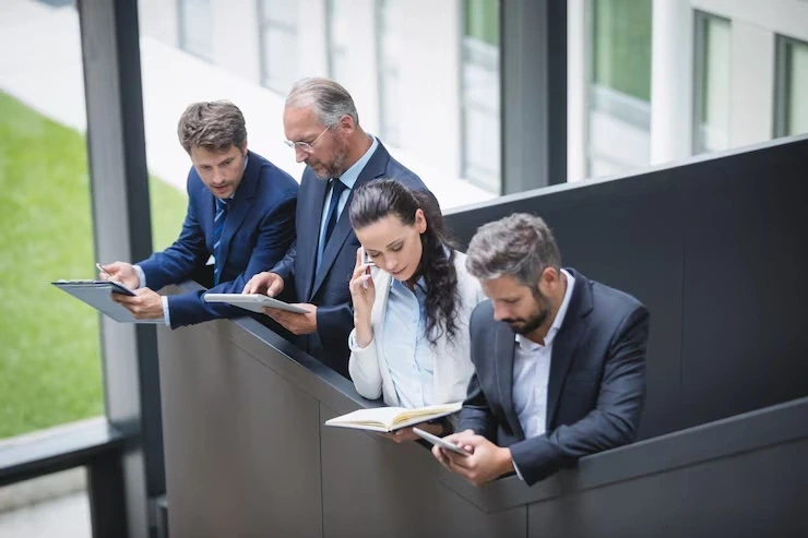 Four professionals reviewing tablets and notes on balcony