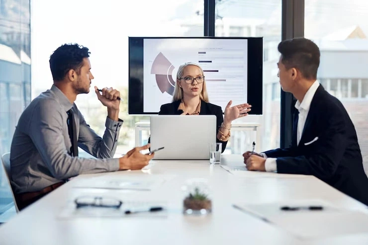 Woman presenting data chart to two colleagues in boardroom