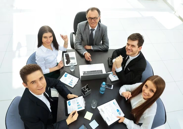 Five professionals reviewing documents at round table