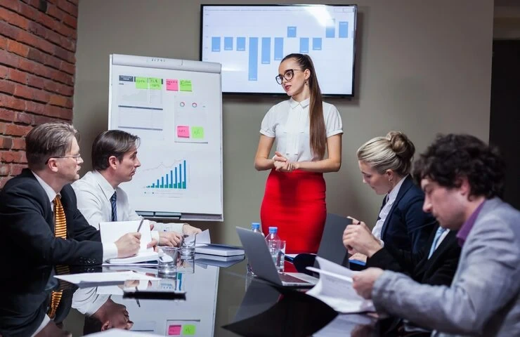 Woman presenting growth charts to business team in boardroom